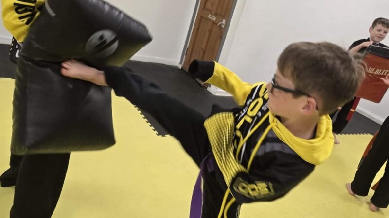 A young SOLO Martial Arts student practicing a confident side kick during training, building strength and focus.
