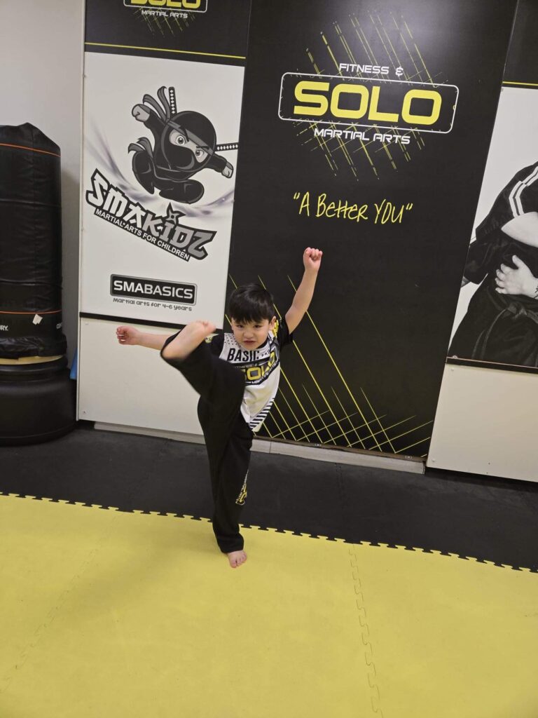 5 year doing a karate kick at SOLO kids Academy